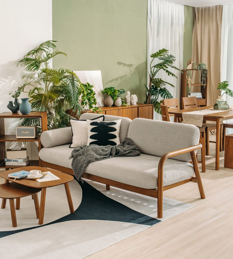 Scanteak teak sofa, nesting tables and dining set in a bright, plant-filled room